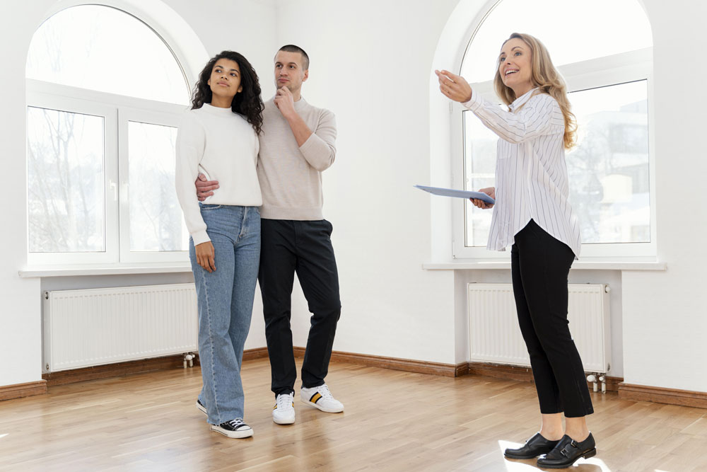 female-realtor-showing-young-couple-new-house